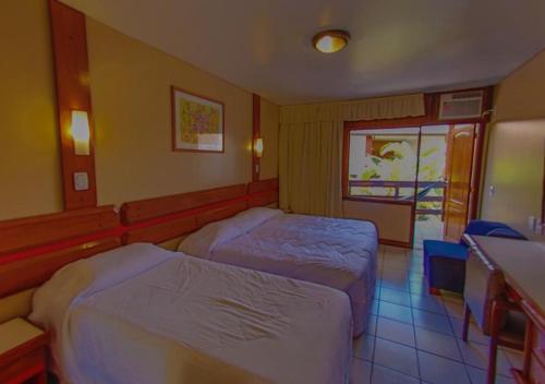 a hotel room with two beds and a window at Costa Cabralia Hotel in Santa Cruz Cabrália