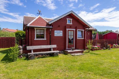 una pequeña casa roja con un banco en el patio en Zur Sonne, en Freest