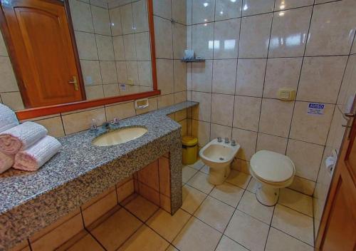 a bathroom with a sink and a toilet and a mirror at Costa Cabralia Hotel in Santa Cruz Cabrália