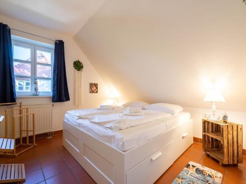 a bedroom with a large white bed and a window at Feriendorf Rugana - Komfort Appartement mit 1 Schlafzimmer B12 in Dranske