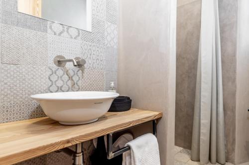 a bathroom with a white bowl sink on a wooden counter at Curt di Clement Eco Mobility Hotel in Tirano