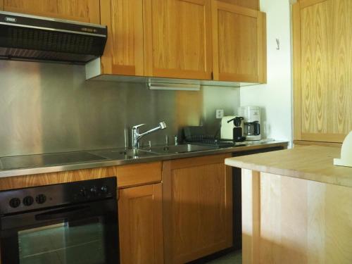 a kitchen with wooden cabinets and a sink at Residenz La Mora in La Punt-Chamues-ch
