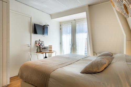 - une chambre avec un lit et une télévision murale dans l'établissement Hotel Pannenkoekhuis Vierwegen, à Domburg