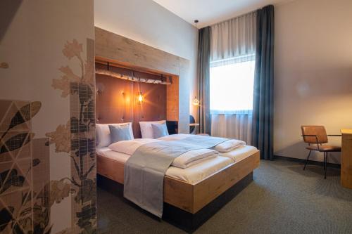 a bedroom with a large bed with a wooden headboard at RiKu HOTEL Göppingen in Göppingen