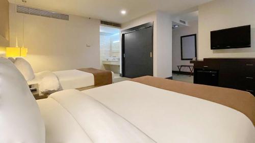 a hotel room with two beds and a flat screen tv at Hotel Trinitarias Suites in Barquisimeto