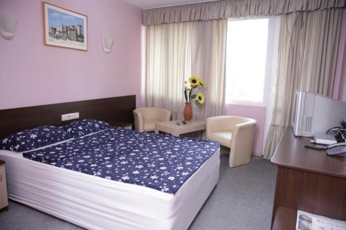een slaapkamer met een bed, een bureau en een televisie bij Family Hotel Avramov in Vidin