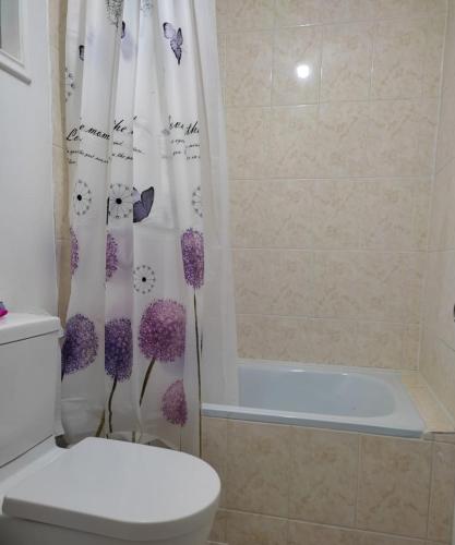 a bathroom with a toilet and a shower curtain with flowers at Hospedaje el Rosario in Angol