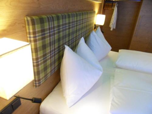 a bed with white pillows in a room at Hotel Garni Siegmundshof - inclusive Joker Card im Sommer in Saalbach Hinterglemm