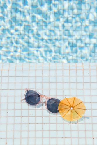 a pair of sunglasses and an umbrella next to a swimming pool at Novotel Monte-Carlo in Monte Carlo
