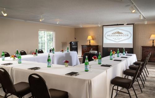 a meeting room with white tables and chairs and a screen at Meadowbrook Inn in Blowing Rock