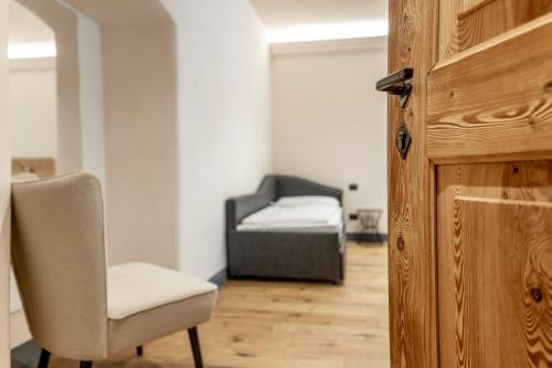 a room with a bed and a chair and a door at Curt di Clement Eco Mobility Hotel in Tirano