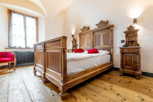 a bedroom with a large wooden bed with red pillows at Curt di Clement Eco Mobility Hotel in Tirano