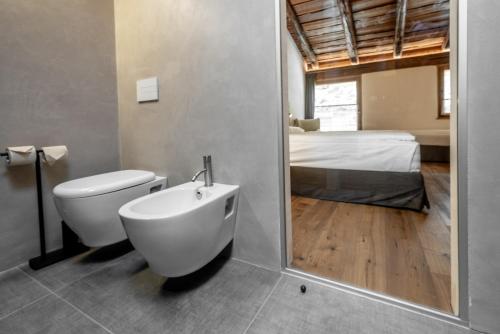 a bathroom with a tub and a toilet and a bed at Curt di Clement Eco Mobility Hotel in Tirano