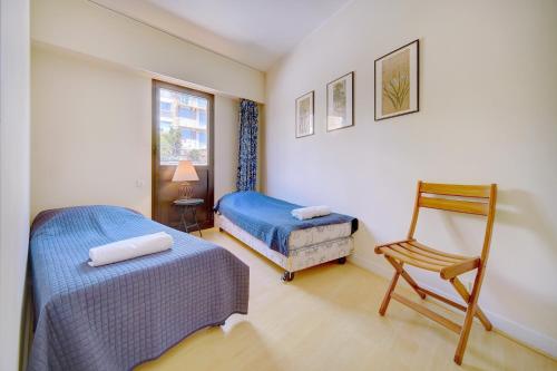 sypialnia z 2 łóżkami, krzesłem i oknem w obiekcie 3 bedrooms Cannes Center south terrace w Cannes