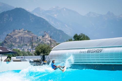 a man riding a wave in the water next to a trailer at Alaïa Lodge in Crans-Montana