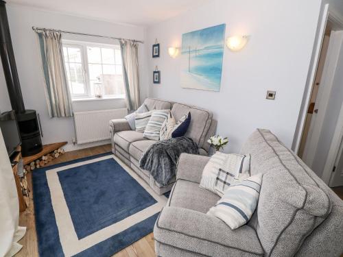a living room with a couch and a blue rug at Ty Bach, 1 bedroom home with hot tub and views in Bettws-yn-Rhôs