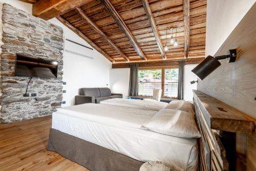 a bedroom with a large bed and a stone wall at Curt di Clement Eco Mobility Hotel in Tirano