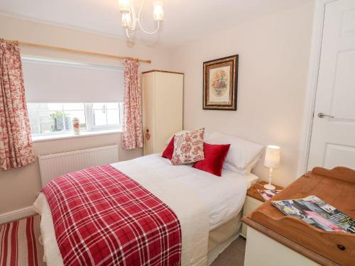a bedroom with a bed with red pillows and a window at Ty Bach, 1 bedroom home with hot tub and views in Bettws-yn-Rhôs