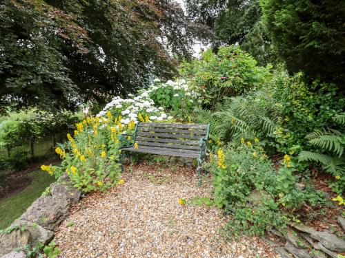 a wooden bench sitting in a garden with flowers at The Carriage in Lydney