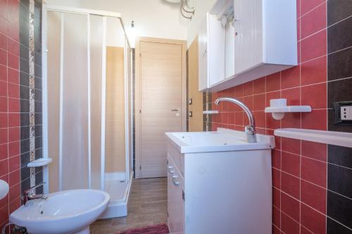 a bathroom with a sink and a toilet and red tiles at Casa Vacanza Josephine in Barcellona-Pozzo di Gotto