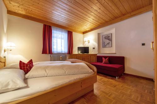 a bedroom with a large bed and a red couch at Chalet Alpina in Ortisei