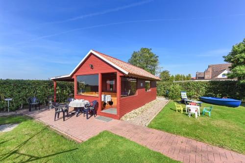 un pequeño cobertizo rojo con mesa y sillas en Friesenmeer Ferienwohnung Vier, en Bensersiel