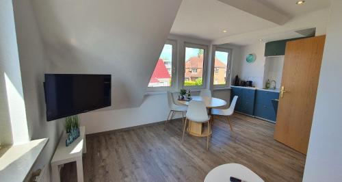 a living room with a television and a table and chairs at Friesenmeer Ferienwohnung Vier in Bensersiel