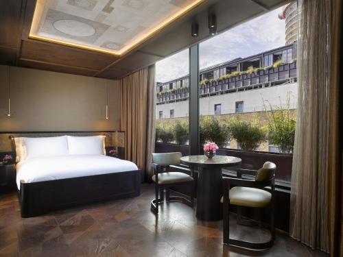 a hotel room with a bed and a table and a window at Nobu Hotel London Shoreditch in London
