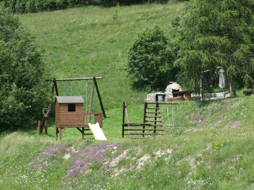 a playground with a swing and a house on a hill at Residenz La Mora in La Punt-Chamues-ch