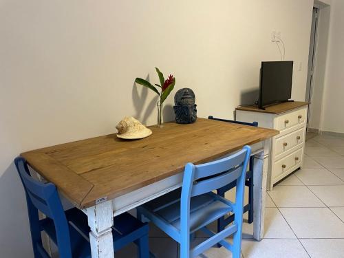 mesa de madera con 2 sillas azules y TV en Santa Hospedaria Beach en Bertioga