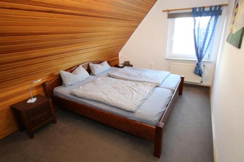 ein Schlafzimmer mit einem Bett mit einem Kopfteil aus Holz in der Unterkunft Frankenhuus in Krummhörn