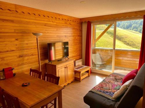 a living room with a couch and a tv and a table at La Foux 2 pièces in Allos