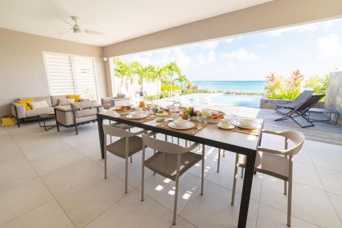 a dining room with a table and a view of the ocean at Eden Roc Villas in Le Diamant