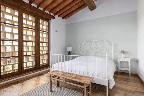 um quarto com uma grande cama branca e um banco em IL PODERINO - LUSSUOSO CASOLARE DI DESIGN em San Gimignano