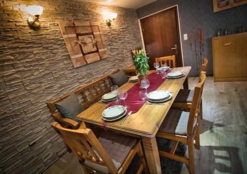 a wooden dining room table with chairs and a brick wall at Im Vulkanland Fewo bis 6 Personen in Ettringen