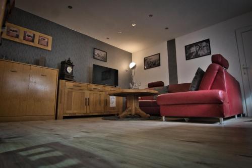 a living room with a red couch and a table at Im Vulkanland Fewo bis 6 Personen in Ettringen