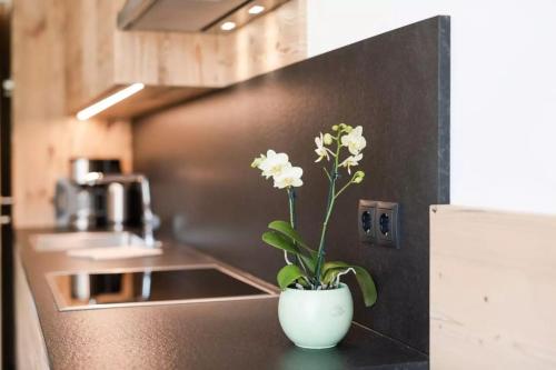 a white vase with white flowers on a kitchen counter at Natur Suite Edelweisshof App Ferdi in Chiusa