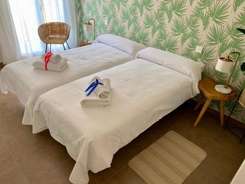 two beds in a room with white sheets and towels at Sea to Sky Suites - Mijas Pueblo in Mijas