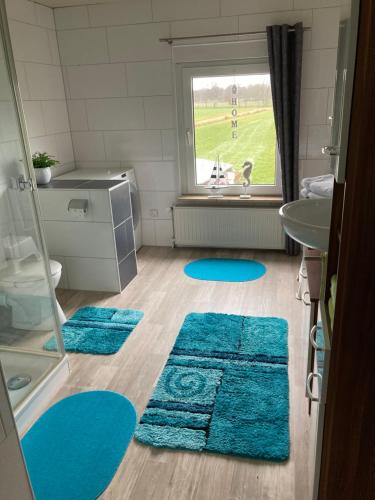 La salle de bains est pourvue de tapis bleus et d'un lavabo. dans l'établissement FeWo Landruhe, à Aurich