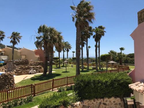 a park with palm trees and a fence at ATICOS Primera Linea en ZAHARA DE LOS ATUNES in Zahara de los Atunes
