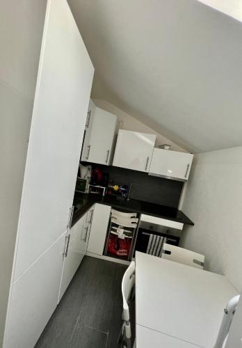 a small kitchen with white cabinets and a table at Pension des Draizes in Neuchâtel