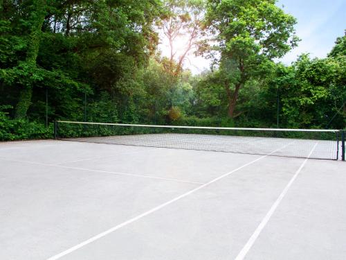 un court de tennis avec un filet et quelques arbres dans l'établissement VILLA AVEC PISCINE PRIVEE, à Auberville