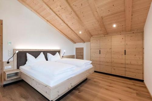 Schlafzimmer mit einem großen weißen Bett und Holzböden in der Unterkunft Natur Suite Edelweisshof App Tony in Klausen
