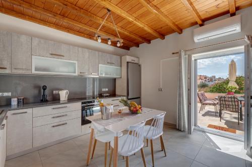 a kitchen with a table with white chairs and a view at TAKIS GUESTHOUSE-Orneda-HERMOUPOLIS in Ermoupoli