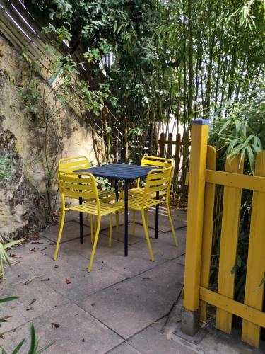 a table with four yellow chairs and a fence at Le Gite de la Loire in Rochecorbon