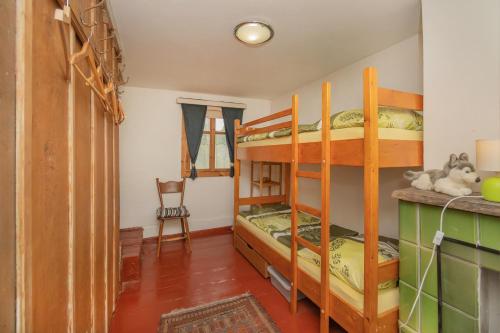 ein Schlafzimmer mit Etagenbetten und ein Zimmer mit einem Stuhl in der Unterkunft Chalupa u kostela in Chřibská