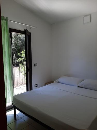 a white bed in a room with a window at Residence Eden in Marina di Camerota