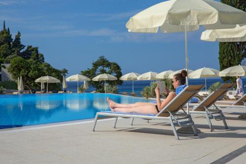 a woman laying on a chair next to a swimming pool at Maistra Select Mlini Hotel in Mlini