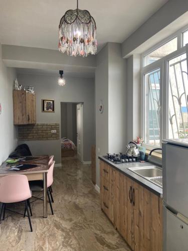 a kitchen with a chandelier and a sink and a table at Apartments on Bakradze in Tbilisi City