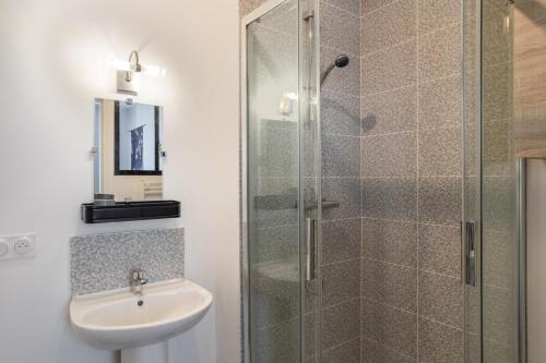 La salle de bains est pourvue d'un lavabo et d'une douche en verre. dans l'établissement YOKOSO - Studio proche CHU avec terrasse, à Rennes